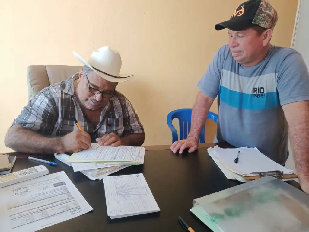 Hombre firmando documentación de su crédito y apoyarse para la compra de insumos