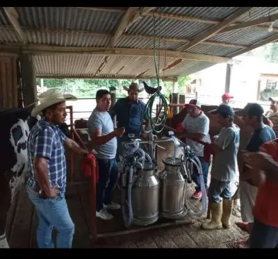 Productores ganaderos en su granja mostrando las ordeñadoras portátiles de los cuales fueron beneficiados