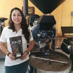Mujer productora cafetalera mostrando orgullosa el resultado de su esfuerzo