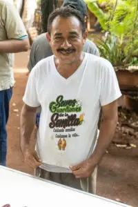 Productor rural sonríe mientras muestra una camiseta con el mensaje "Somos Guardianes de la Semilla", promoviendo la conservación de semillas nativas y la biodiversidad agrícola.