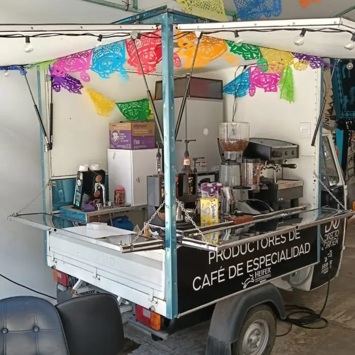 Interior de una motocafetería equipada con máquina de espresso, molino, refrigerador y estación de preparación para servir café de especialidad.