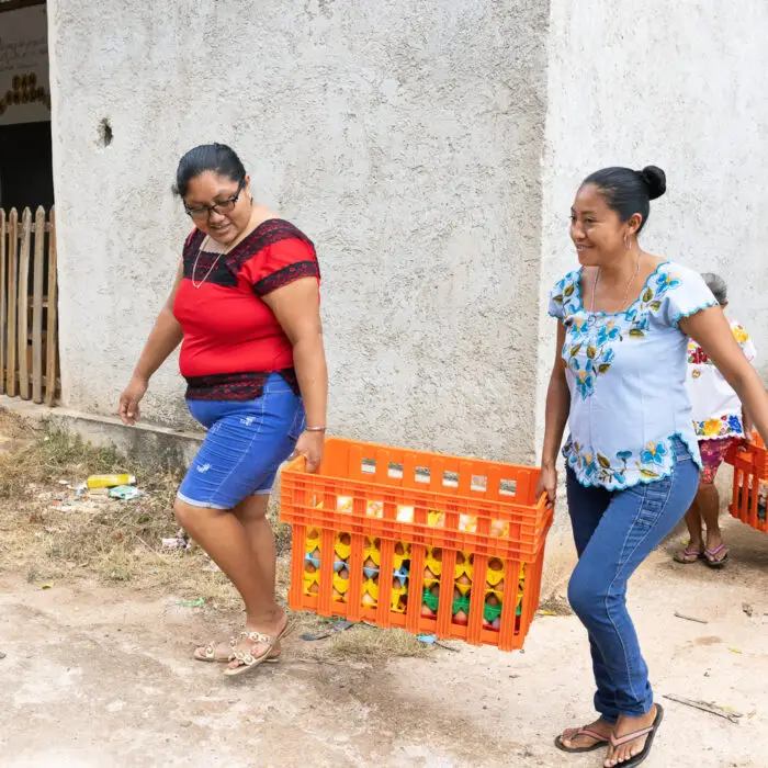 Productoras cargando cajas con huevos frescos para su comercialización local.