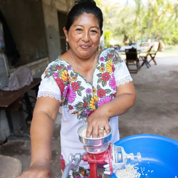 Productora moliendo maíz para preparar alimento destinado a sus gallinas.